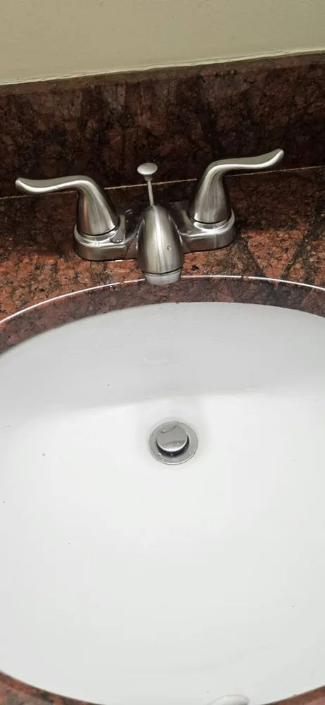 Brushed nickel two-handle faucet installed on a white sink in a granite counter